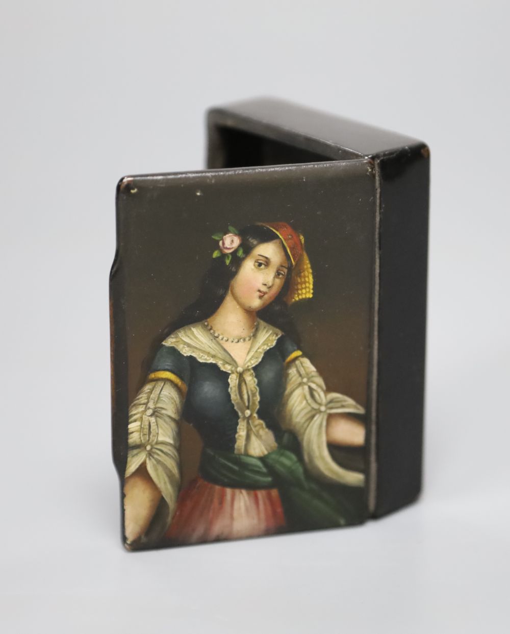 A papier mache snuff box with a portrait of a lady to the lid